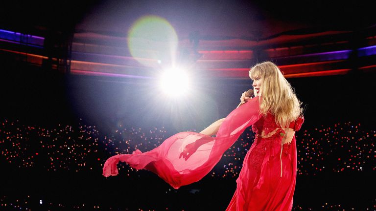 Taylor Swift performing on stage in a billowing red dress